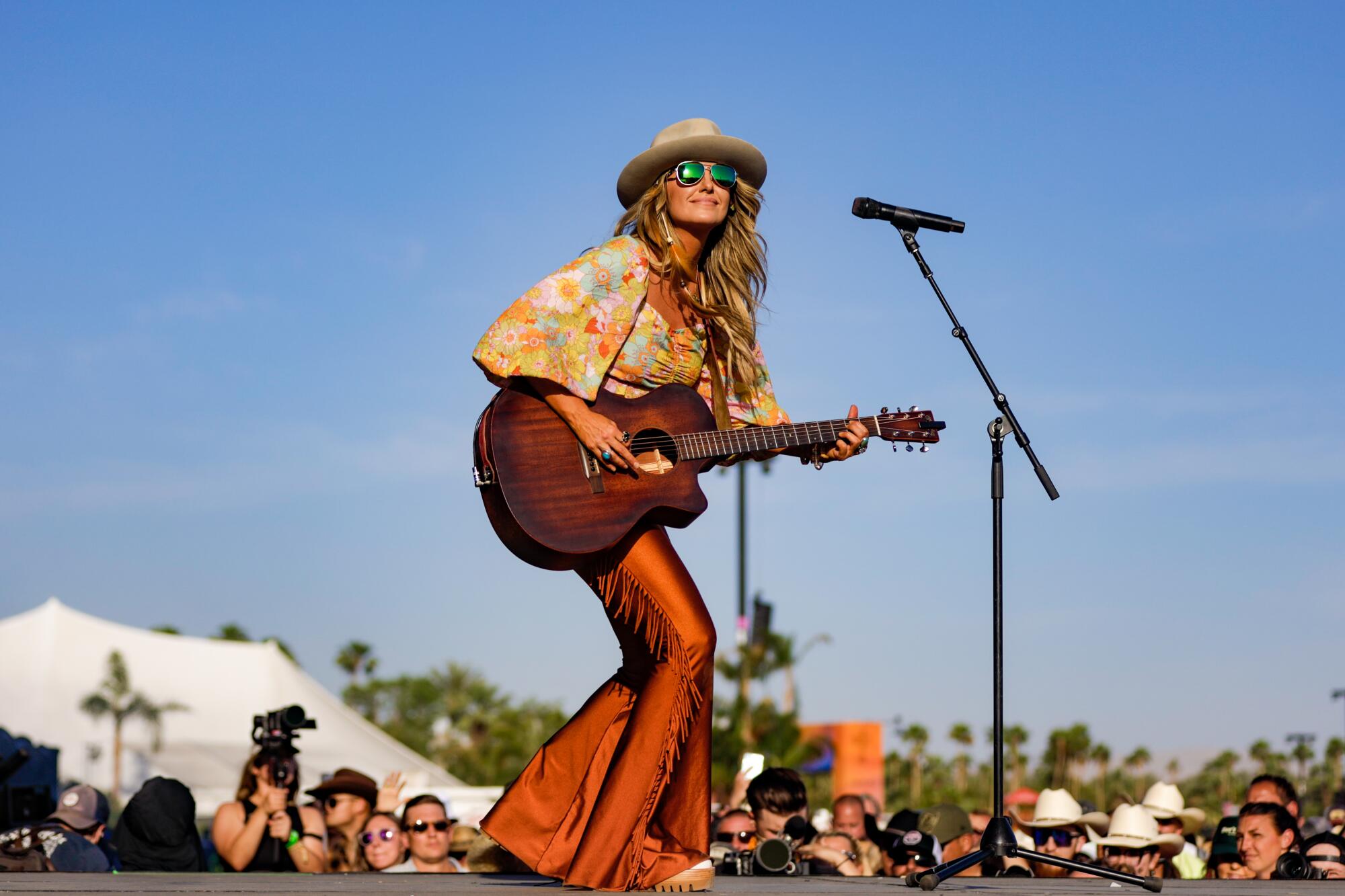 Lainey Wilson holds a guitar and performs on stage