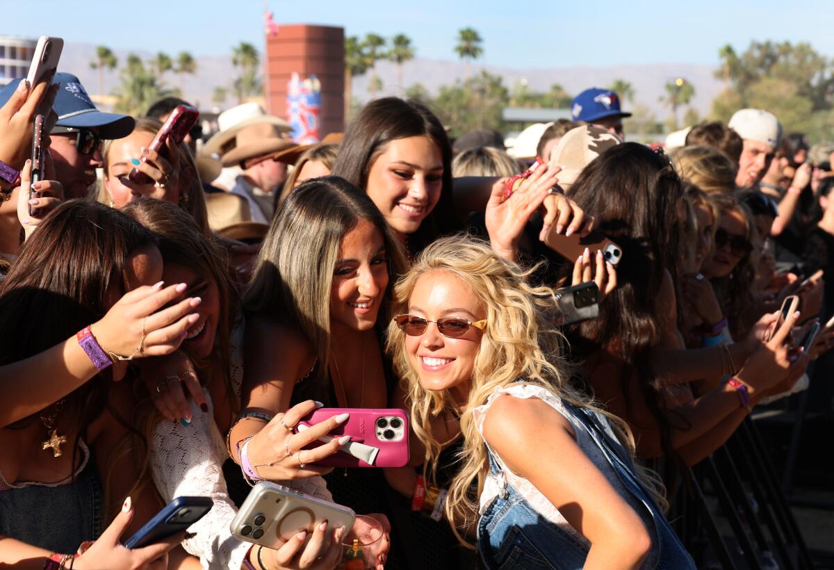 Actress Sydney Sweeney takes photos with fans in a concert crowd