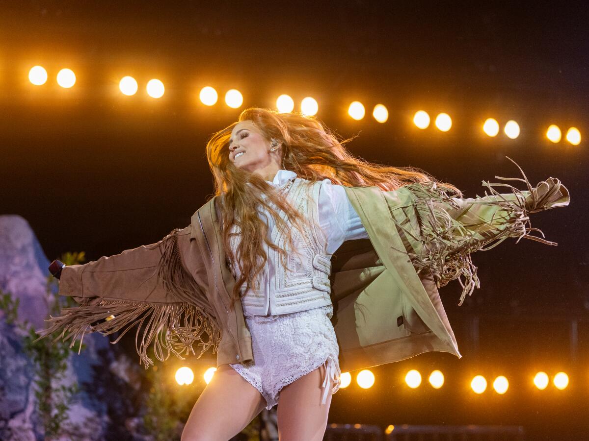 Ashlee Simpson holds out her arms as she dances, wearing a big brown fringed jacket