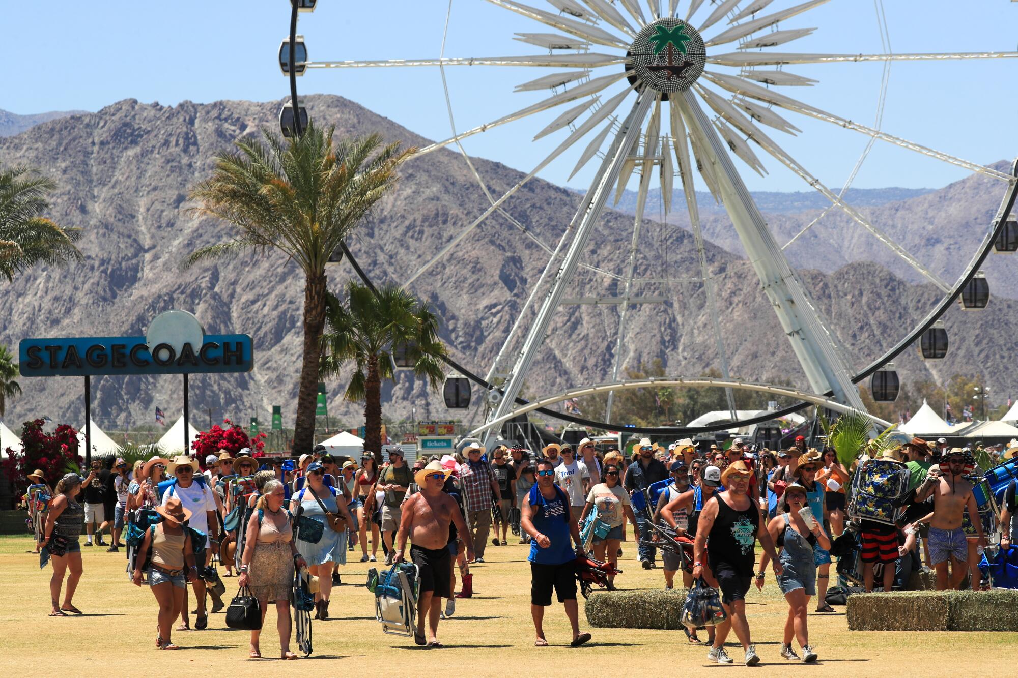 People walk in front of the ferris wheel at Stagecoach