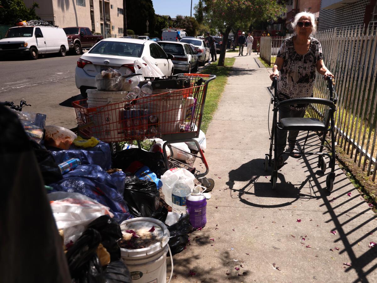 A woman pushes her walker past debris in Los Angeles.