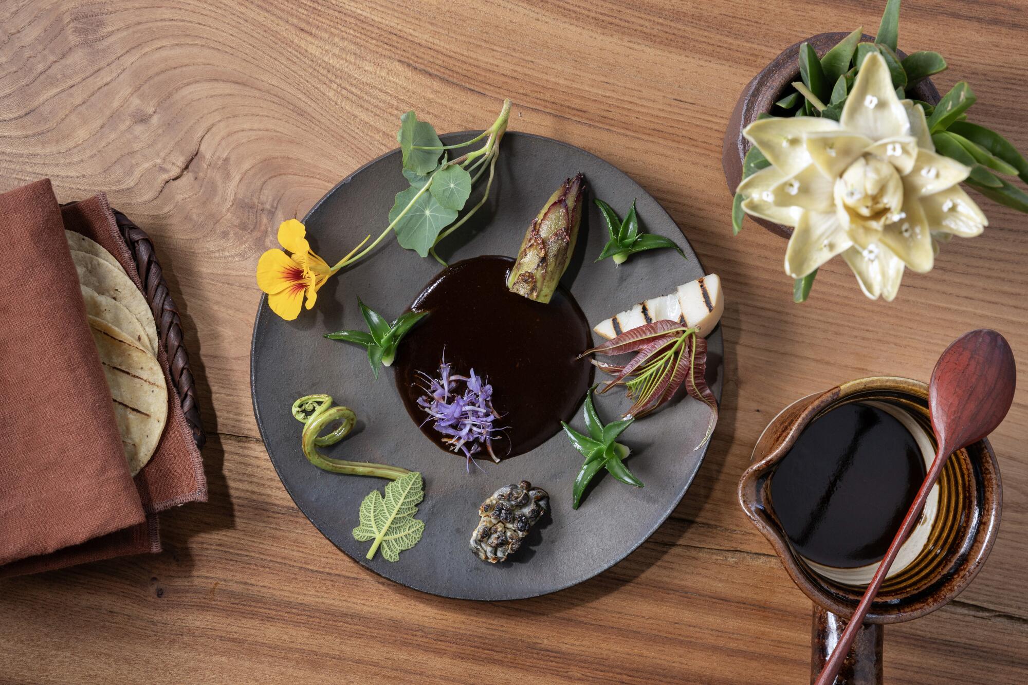 Mole with garnishes of local flora, served with tortillas and an artichoke fashioned as a flower.