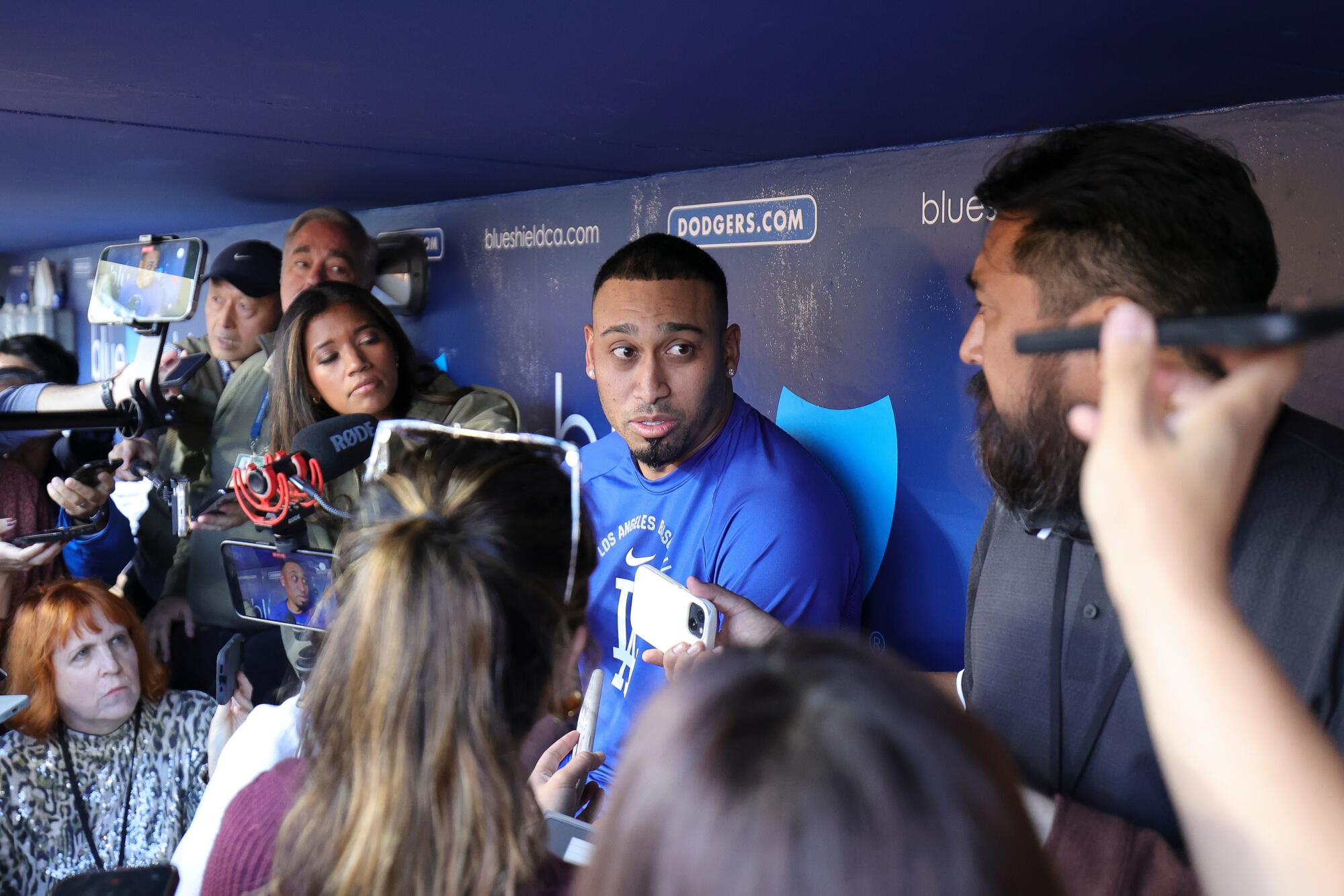 Dodgers closer Edwin Díaz, center, speaks to reporters in the dugout before a game between the Dodgers and Miami Marlins.