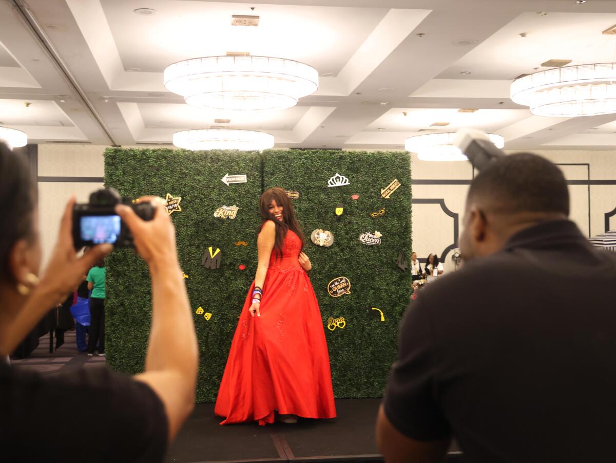 A teenager models a red dress for photographers.