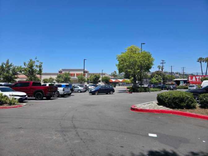A parking lot is seen lined with trees filled with cars.