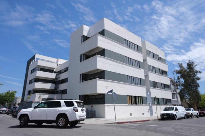 An apartment building painted white and black is seen on a block in Hollywood.