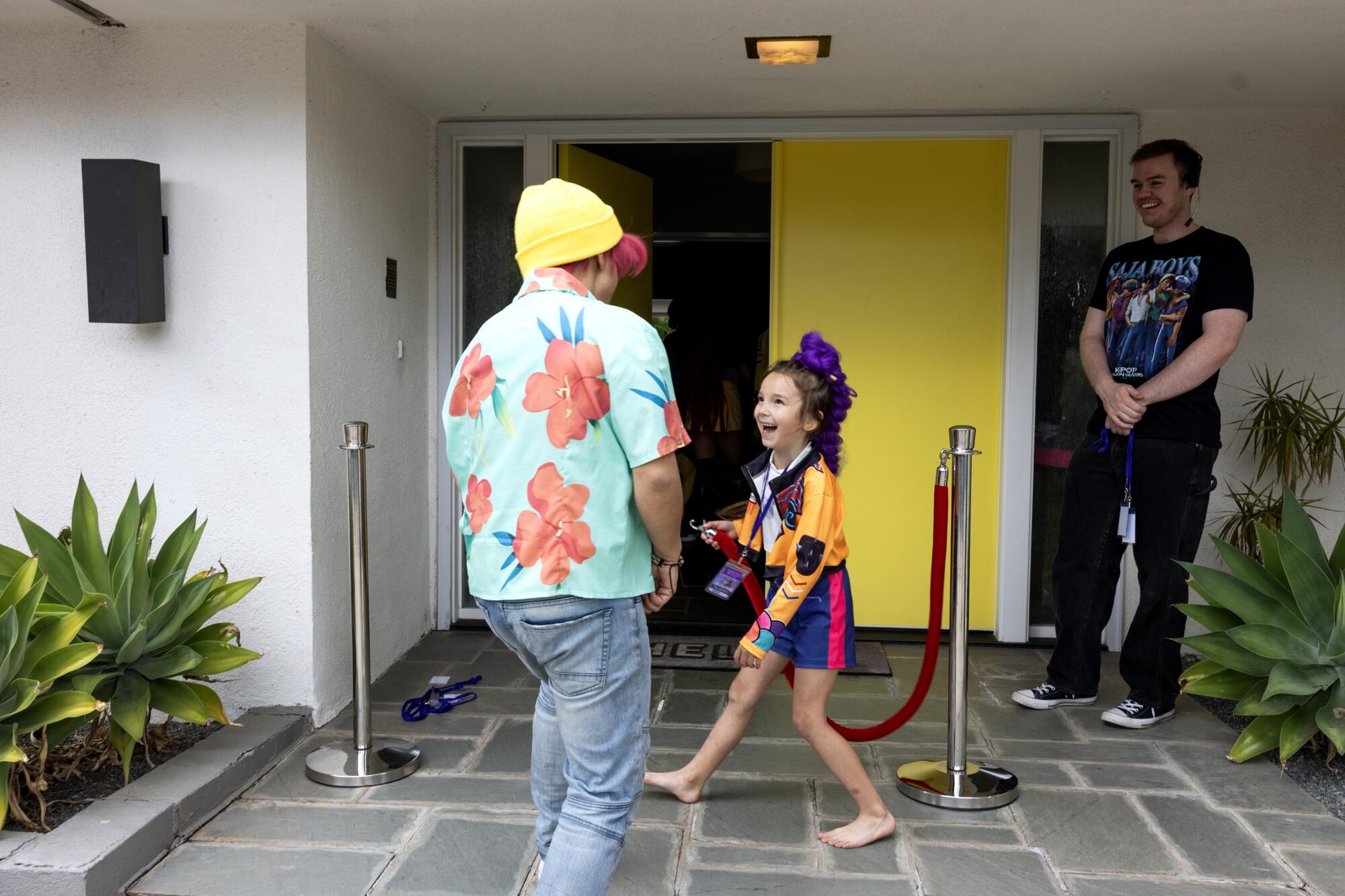 A girl holds a red rope for an entertainer at her front door.
