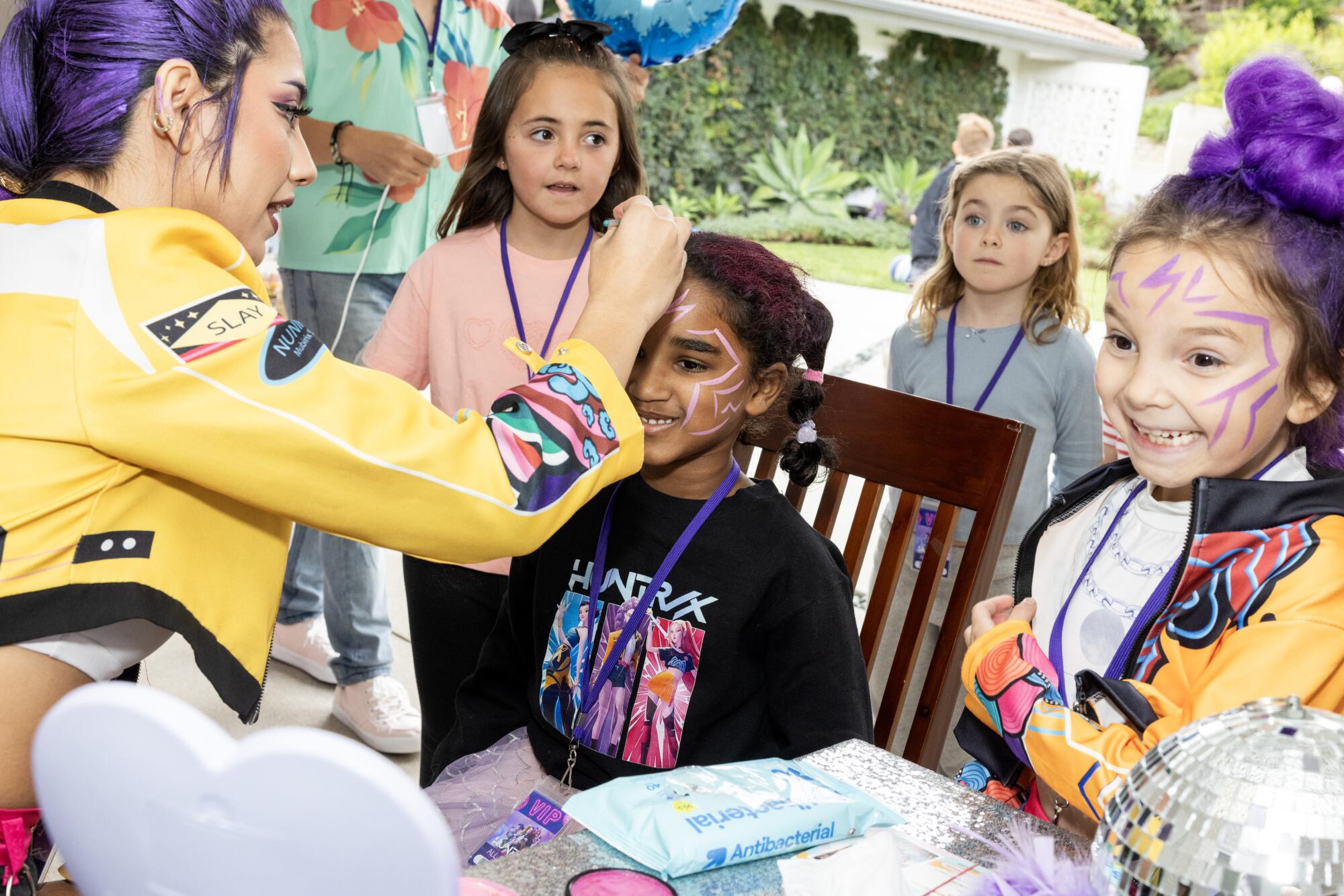 Eliana Fraser, dressed in a Rumi costume, paints 6-year-old Ariya Taylor's face at a party for Parker Apel, right.