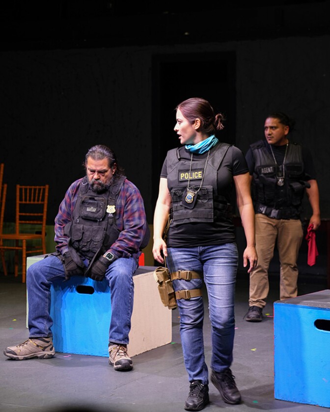 Actors dressed as police officers stand on stage