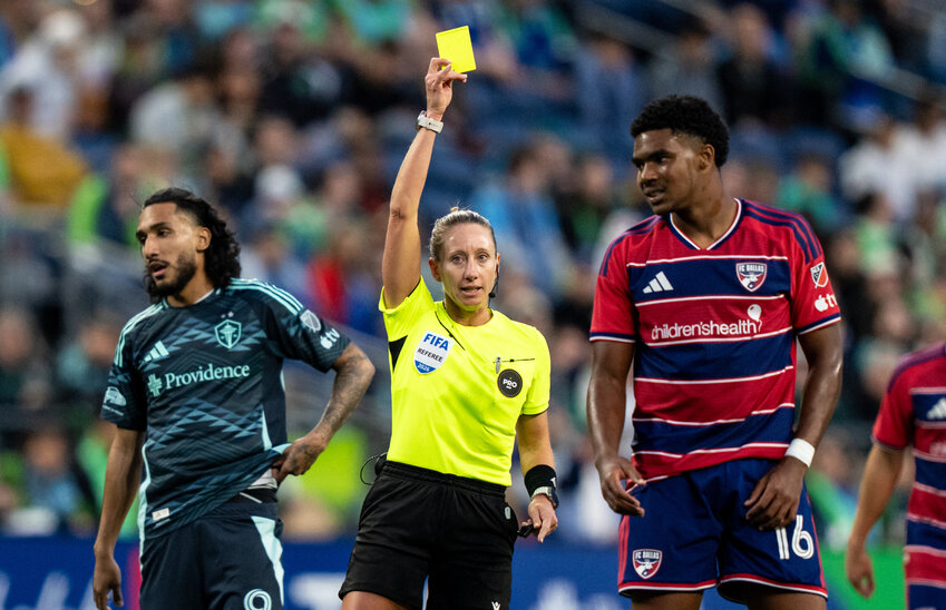 Referee Tori Penso, center, issues a yellow card to FC Dallas forward Nicholas Simmonds (16) during the first half against Seattle Sounders at Lumen Field.