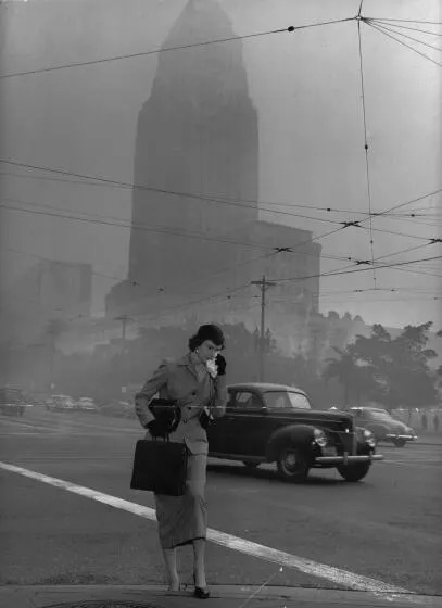 Los Angeles, California, February 4, 1953 - Marian E. Lent walks to work on the morning for Feb. 4, 1953, as the City Hall building is seen through the smog-filled skies in downtown Los Angeles. Photo Credit: R.L. Oliver/ Los Angeles Times