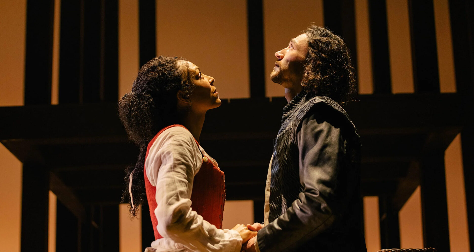 A man in blue and a woman with a flower crown look upward