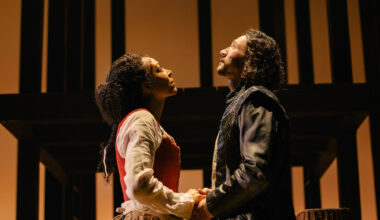 A man in blue and a woman with a flower crown look upward