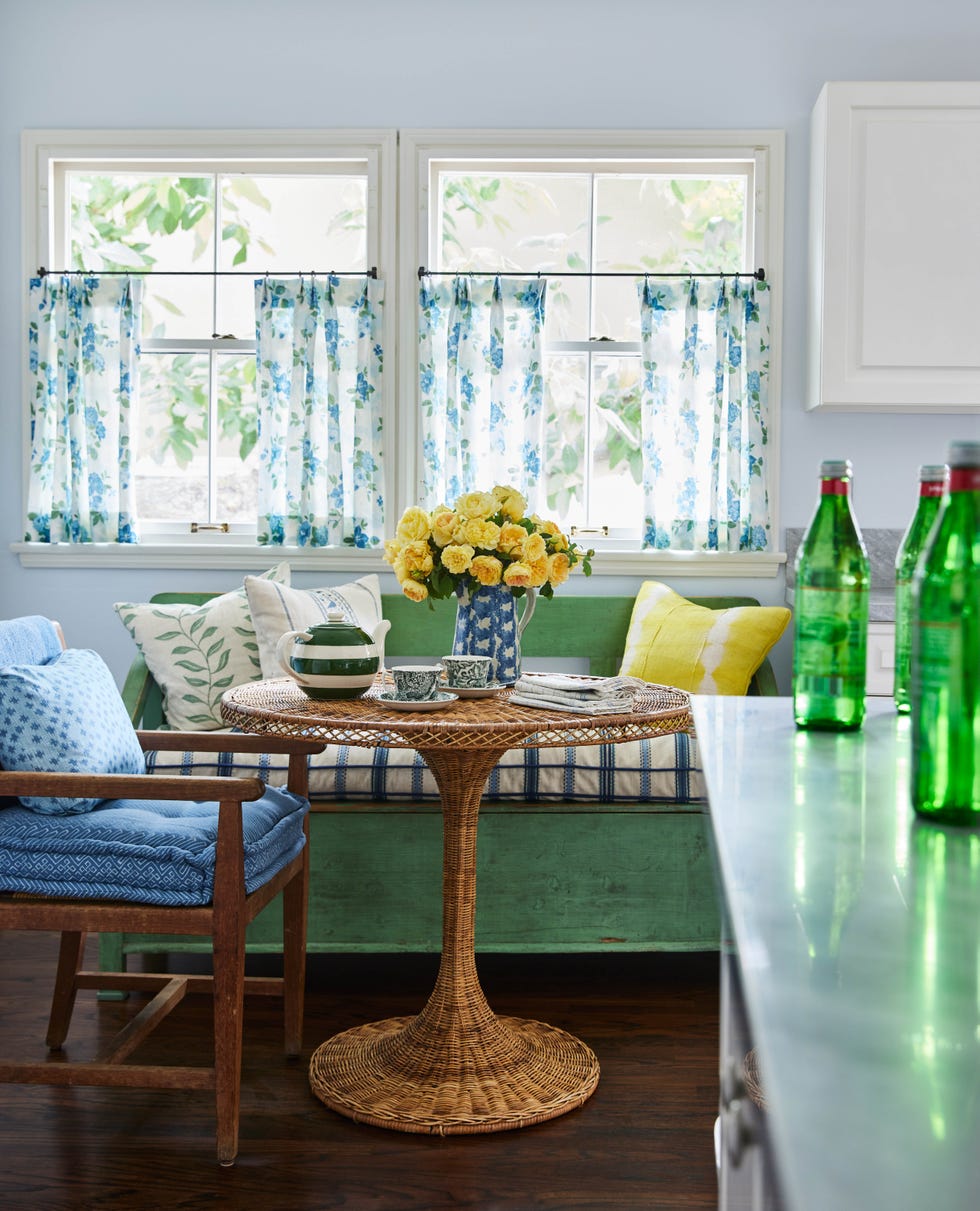Cozy dining area with floral curtains and a round wicker table.