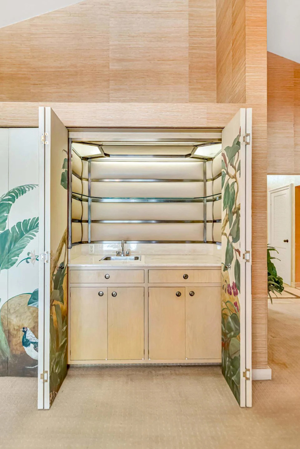 A hand-painted bar with automatic lighting showcases the home’s mid-century modern luxury, inviting guests to step back in time.