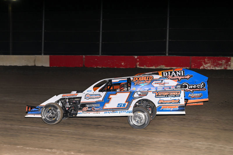 Dirt track race car number 1 on a nighttime race, blue and white livery with sponsor decals.