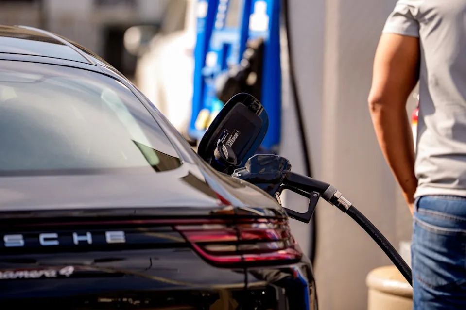 A person fueling a black Porsche at a gas station. Getty Images