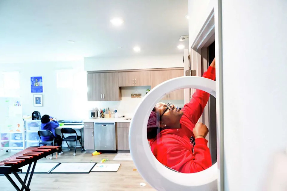 Oakland teacher Melanie Turner does laundry, as son her 9-year-old son Richard Hargraves has a snack in Oakland on Wednesday. (Noah Berger/For the S.F. Chronicle)