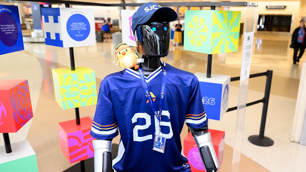 A humanoid robot stands in an airport terminal.