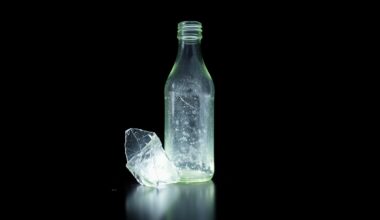An extreme close-up photograph of a broken glass bottle or other piece of physical evidence from the crime scene, lit by a harsh, direct camera flash against a pitch-black background, conveying the gritty, investigative nature of the incident.