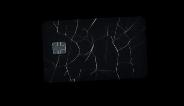 An extreme close-up of a cracked and scratched credit card reflecting a harsh, direct flash of light, conceptually representing the aftermath of a theft and credit card fraud.