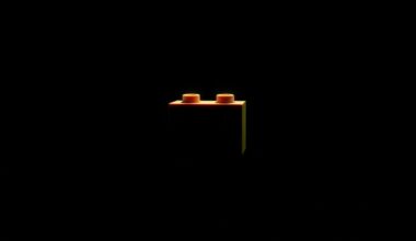 An extreme close-up photograph of a single Lego brick reflecting a bright white light, conceptually illustrating the recovery of stolen goods in a high-profile law enforcement operation.