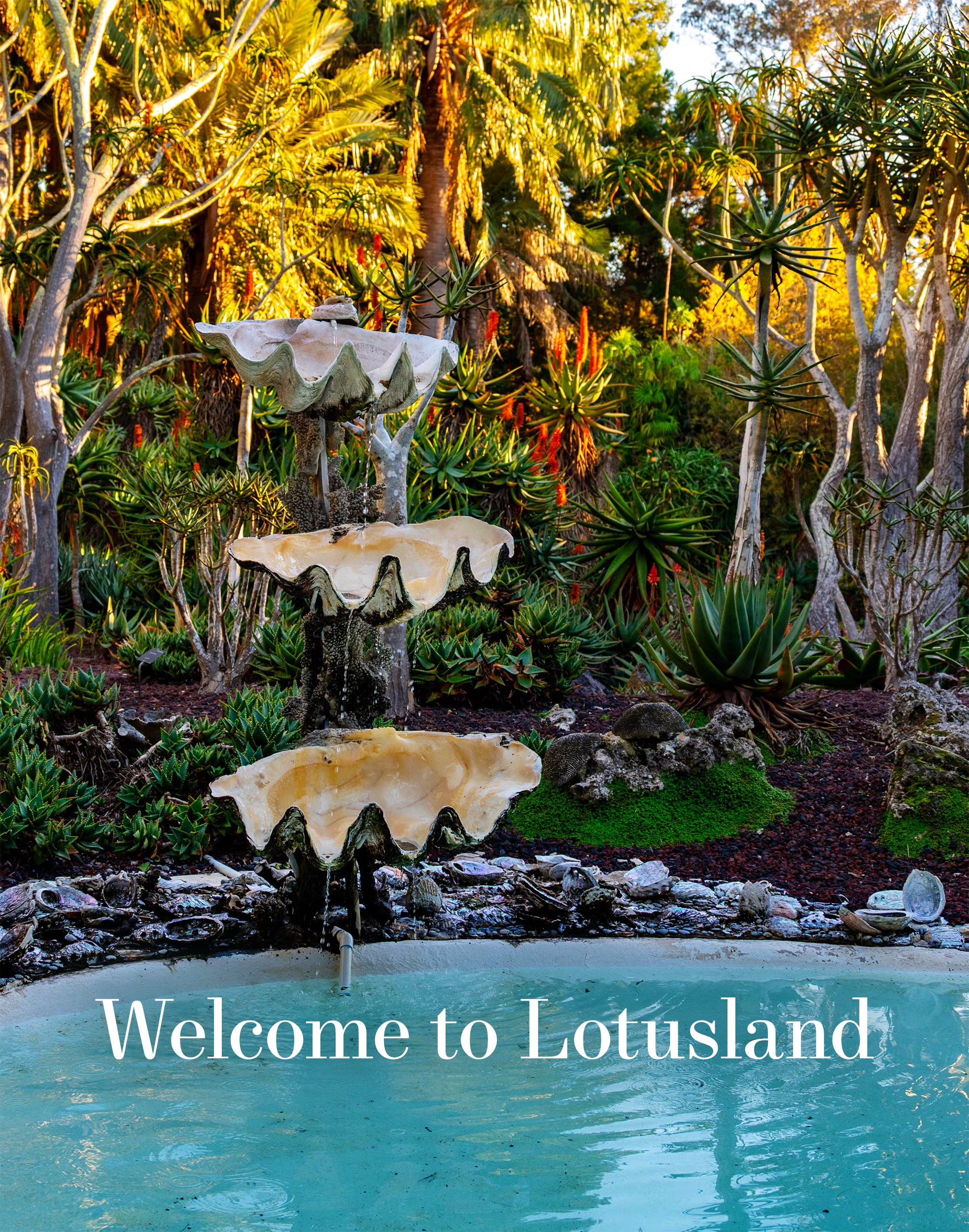 Fountain in a lush garden with a welcome sign.