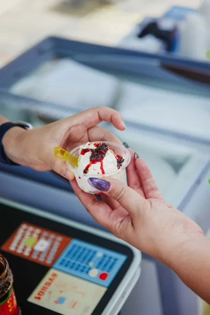 A scoop of a white colored ice cream with a chili crunch sauce on top inside a cup