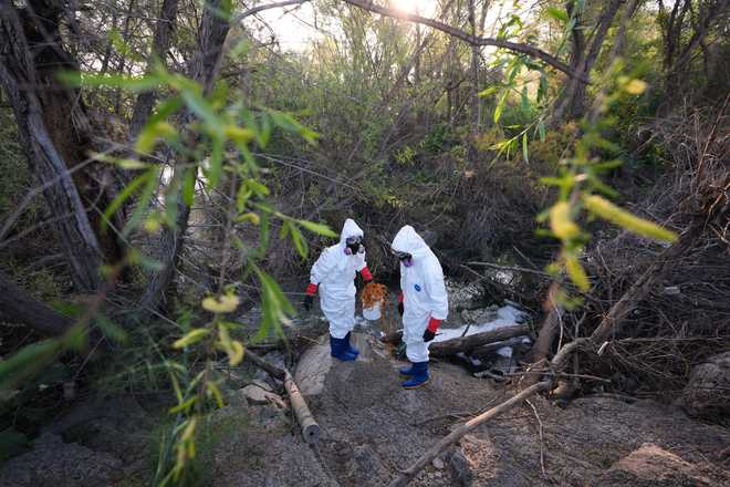 Trent Fry, right, and Leila El Masri collect a water sample of the Tijuana River as part of a research team from the University of California, San Diego, Wednesday, March 11, 2026, in San Diego.