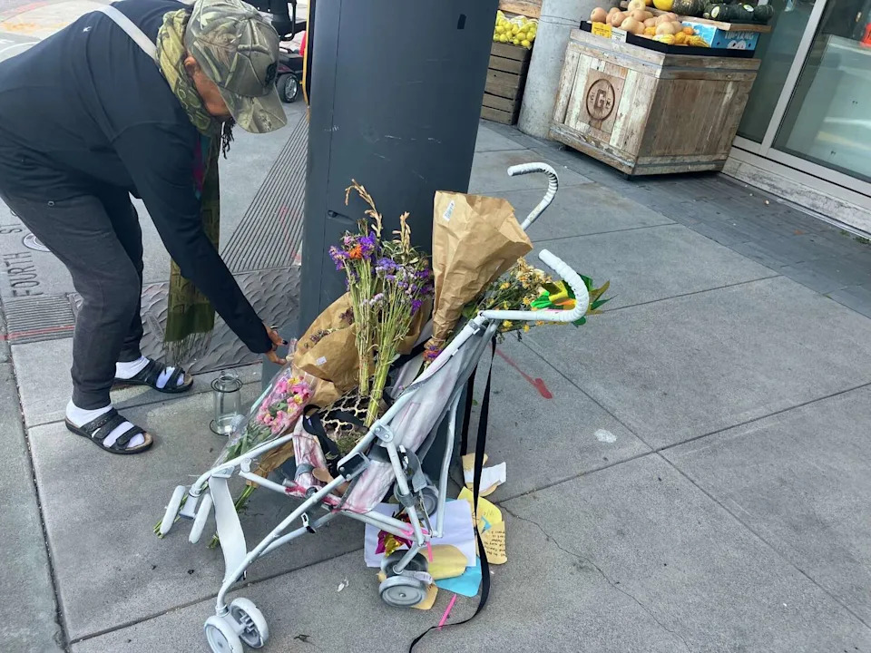 Susan Holder rearranges items at the makeshift shrine for a toddler struck and killed in San Francisco's Mission Bay neighborhood earlier this year. (Rachel Swan / S.F. Chronicle)