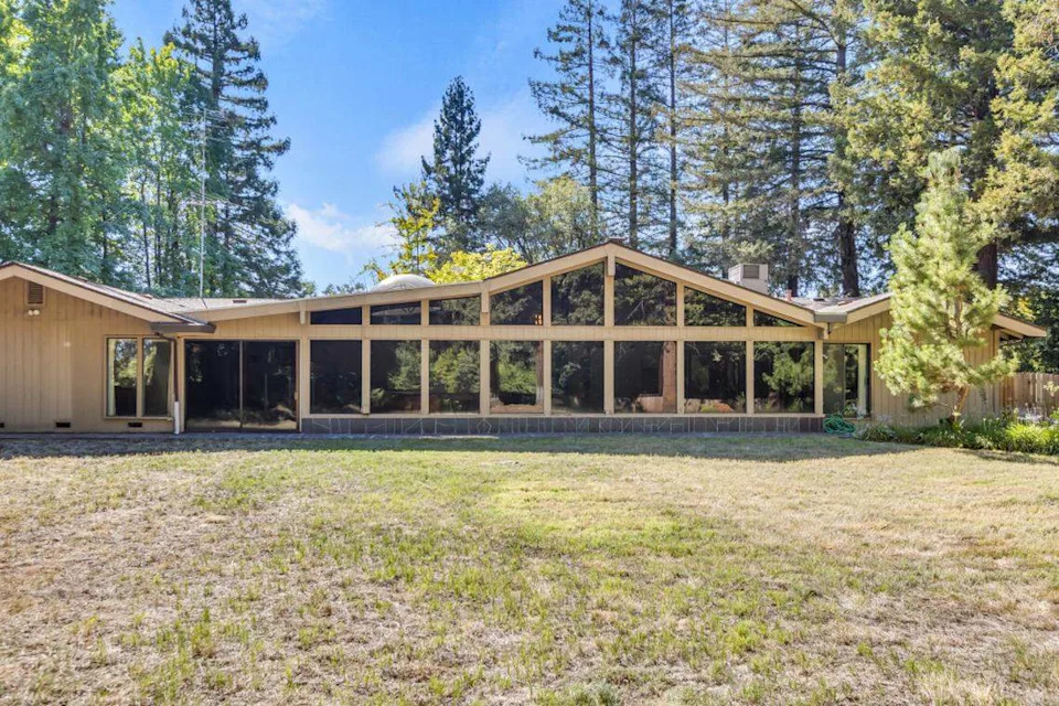 Mature redwood trees frame the 1.3-acre Orangevale property, creating a private woodland setting for this architectural gem.