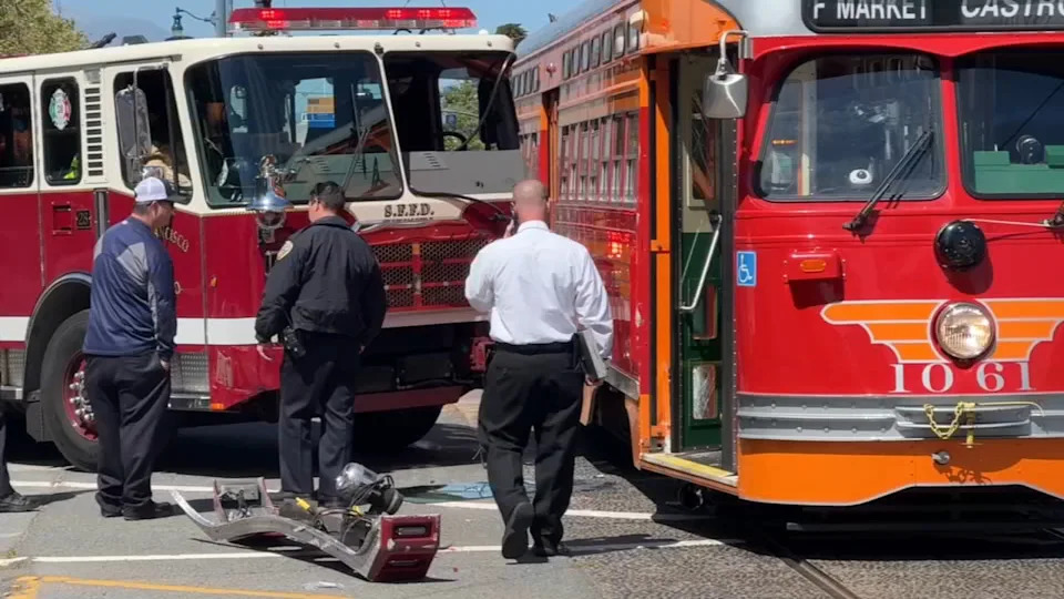 The image shows a San Francisco firetruck crashed into a historic Muni streetcar along the Embarcadero.