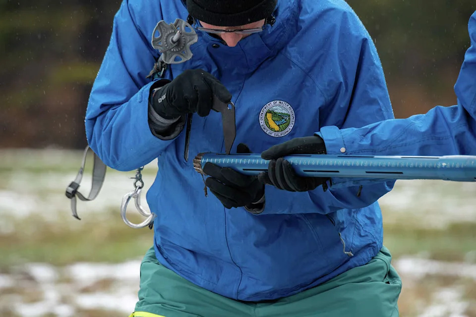 California Cooperative Snow Surveys unit manager Jim Shannon, left, and California Department of Water Resources engineer Jacob Kollen conduct the fourth media snow survey of the 2026 season at Phillips Station, 90 miles east of Sacramento off Highway 50 in El Dorado County in the Sierra Nevada, on April 1, 2026. (Melissa Sanchez Robinson/California Department of Water Resources)