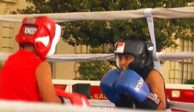 2 kids one wearing red and another wearing blue boxing each other