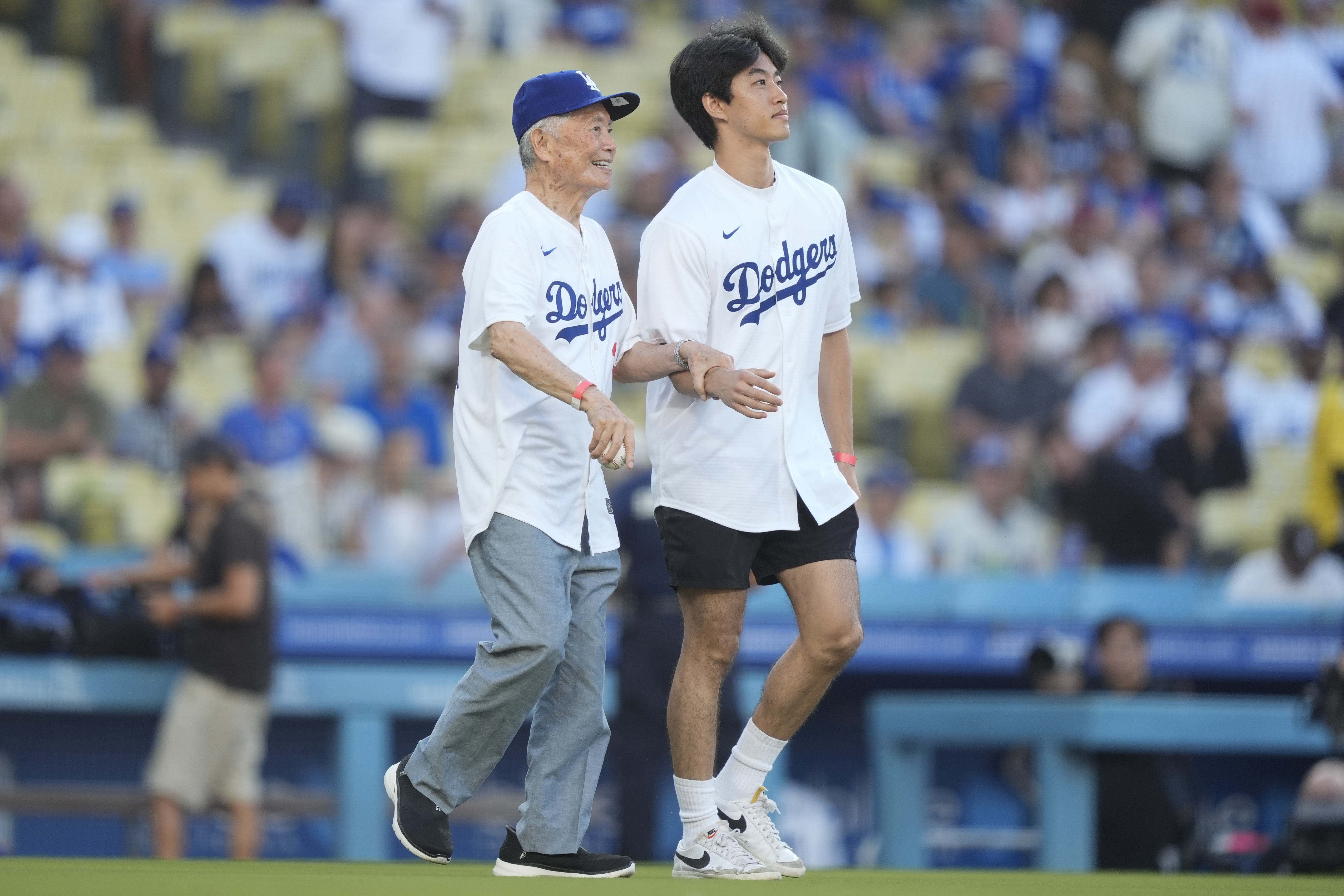 Actor George Takei, left, walks to throw out the first...