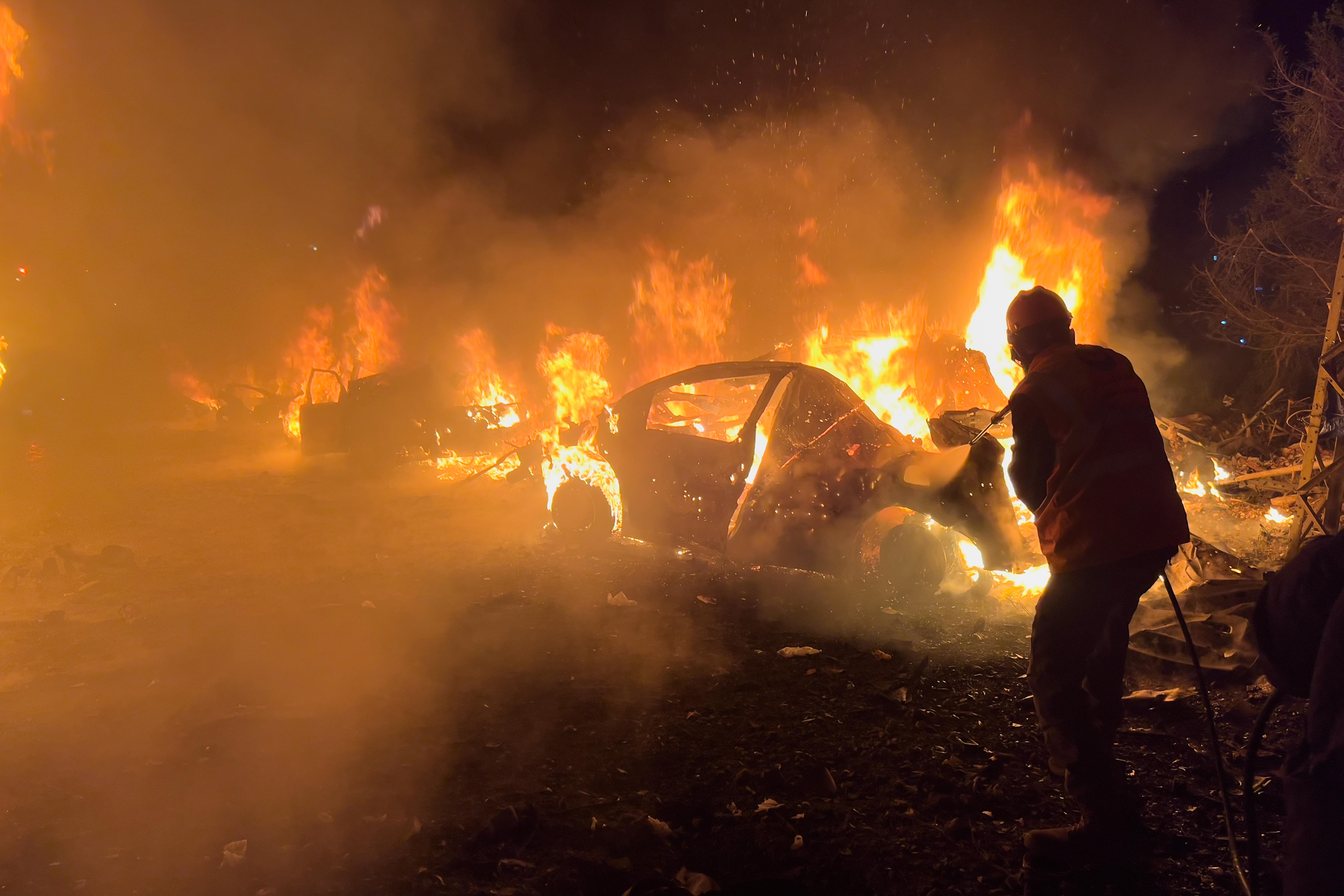 firefighter extinguishes a car at the site of Israeli airstrikes, in Beirut, Lebanon.