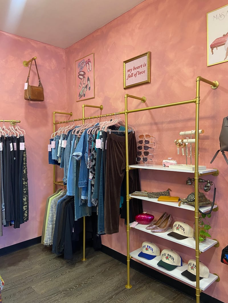 Photo of a corner of a pink store with jeans, shirts, and hats.