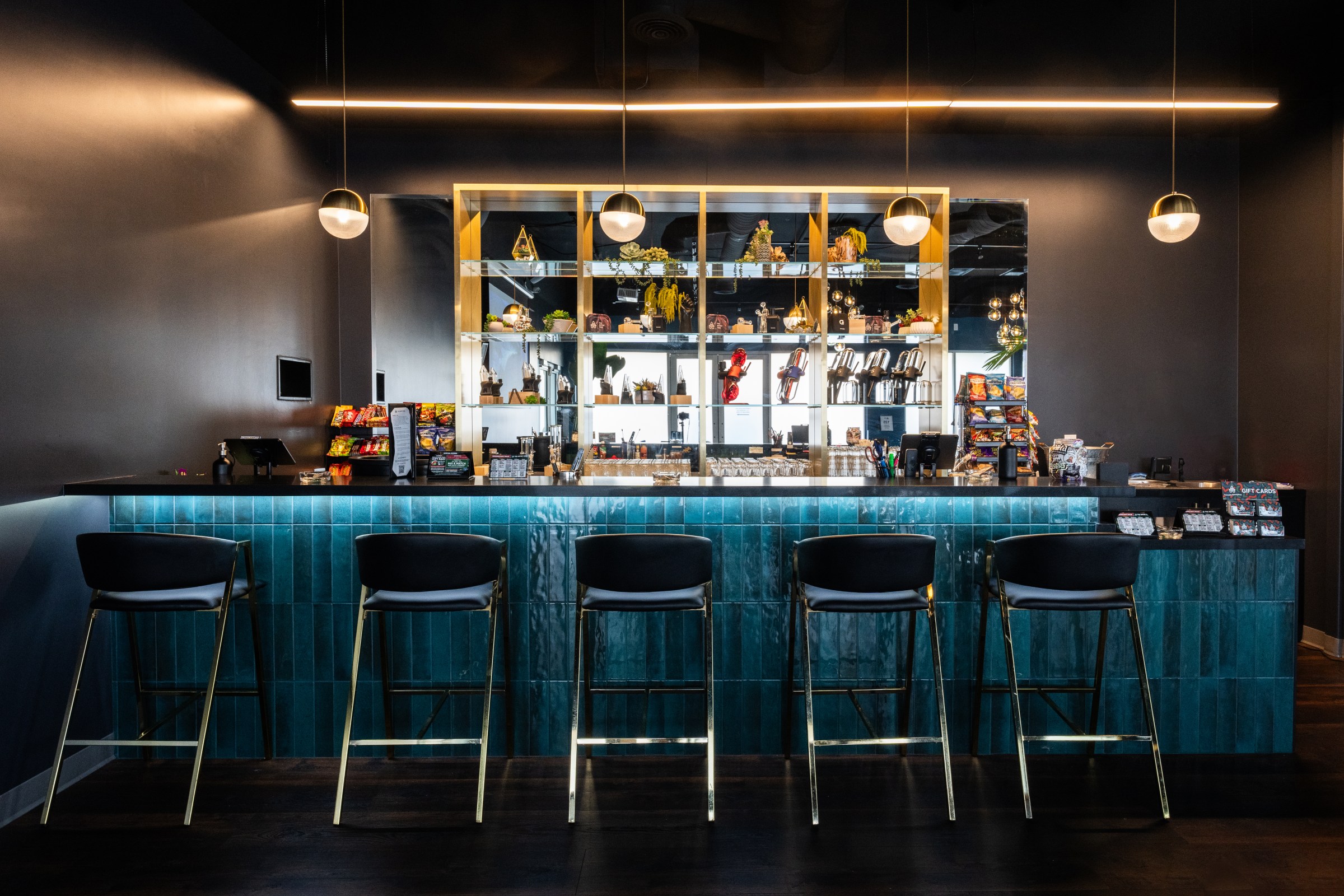 Artist Tree Hawthorne cannabis lounge with green chairs in front of a lit bar in 2025.
