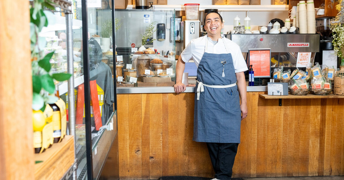A powdered sugar-dusted croissant with orange zest sits on a white plate, next to an éclair topped with cream and orange slices on another white plate.