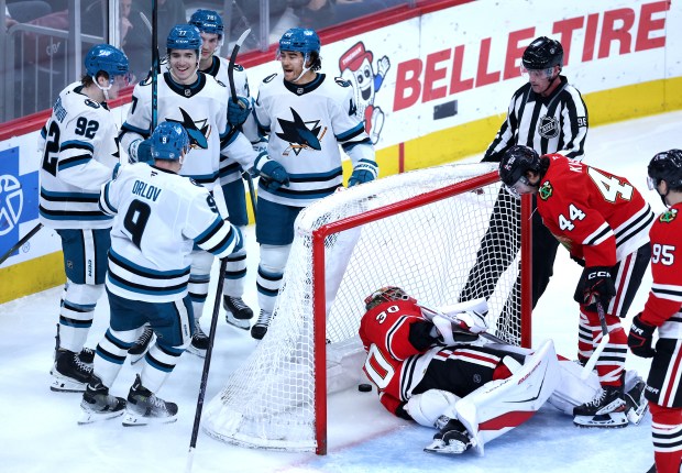 Chicago Blackhawks goaltender Spencer Knight (30) lays on the ice as San Jose Sharks center Michael Misa (77) celebrates with his teammates after Misa scored a goal in the second period of a game at the United Center in Chicago on April 15, 2026. (Chris Sweda/Chicago Tribune)