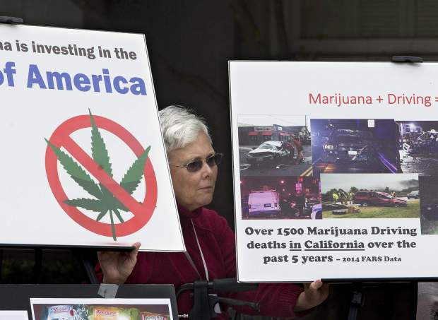 File photo from 2016, Illona Mager holds a pair of signs during a rally against Proposition 64 at the Capitol in Sacramento. (AP Photo/Rich Pedroncelli, File)