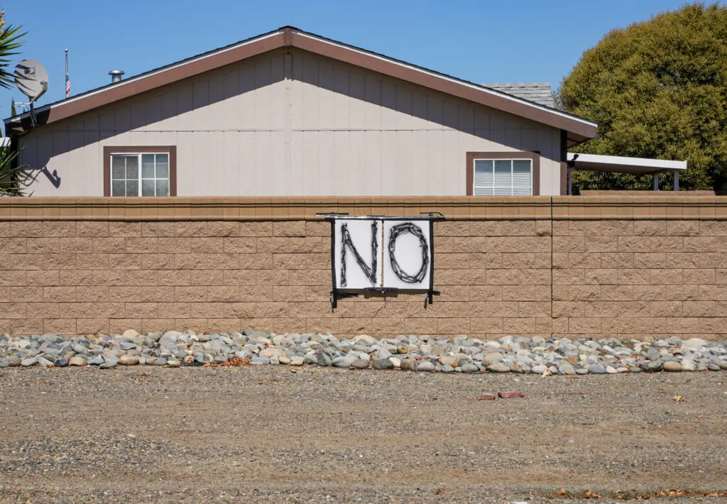 Large poster with the word "NO" taped onto a brick wall with black duct tape.