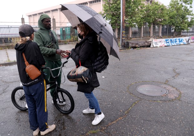 Freelance homeless advocate Amy, left, who preferred to not give her last name, talks with residents Sandra Martin and her boyfriend Drew Dyer, near the Peralta cabins tiny homes where they live at Peralta and Third Streets in Oakland, Calif., on Tuesday, March 31, 2026. The city-contracted tiny home village in West Oakland is slated for closure on March 31. (Jane Tyska/Bay Area News Group)