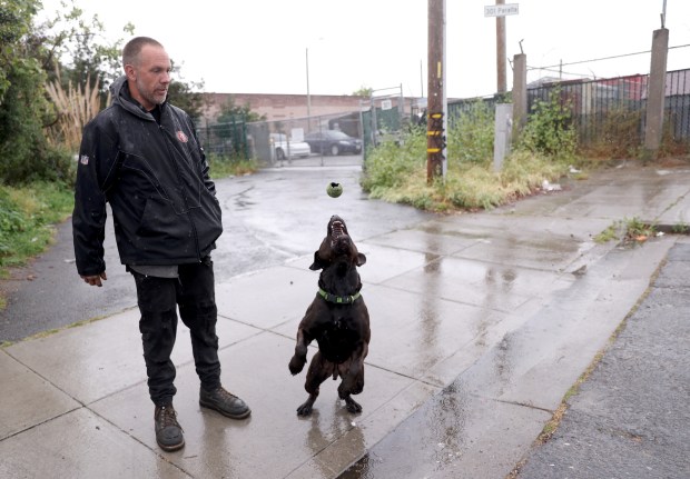 Resident Frank Ernst plays with his dog Bud near the Peralta cabins tiny homes at Peralta and Third Streets in Oakland, Calif., on Tuesday, March 31, 2026. The city-contracted tiny home village in West Oakland is slated for closure on March 31. (Jane Tyska/Bay Area News Group)