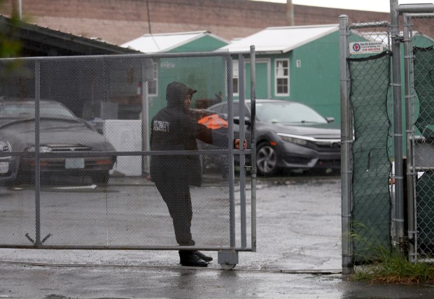 A security guard closes the gate of the Peralta cabins tiny homes at Peralta and Third Streets in Oakland, Calif., on Tuesday, March 31, 2026. The city-contracted tiny home village in West Oakland is slated for closure on March 31. (Jane Tyska/Bay Area News Group)