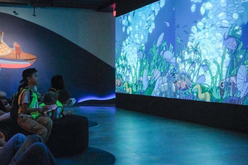 Visitors watch scenes from "Ponyo" unfold across a large projection screen.