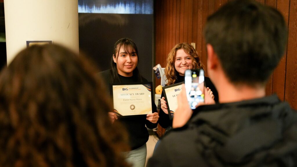 Esme Mora holds a certificate and smiles at an award ceremony for the HOPE Scholars program