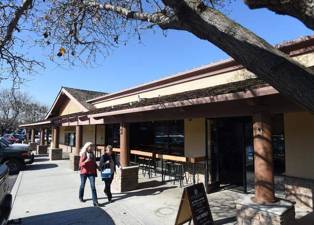 Shoppers stroll by Out of the Barrel Taproom at Fresno’s Fig Garden Village.