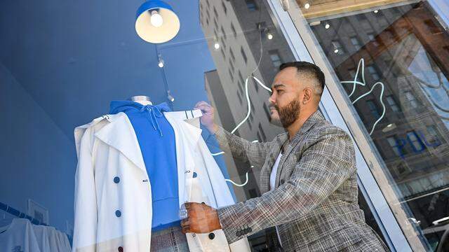 Pablo Leon of Mundo Pol adjusts a coat displayed in the window of the business located in the Warnors Theatre building in downtown Fresno. 
