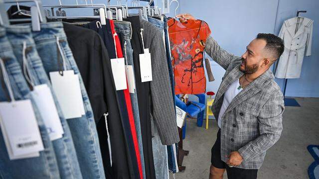 Pablo Leon of Mundo Pol sorts through some of the fashion styles the business offers along with art and design creations in their Warnors Theatre building location in downtown Fresno. 